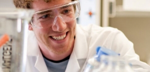 Smiling student in safety goggles and lab coat