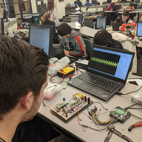 Students working in lab with electronics connected to laptops