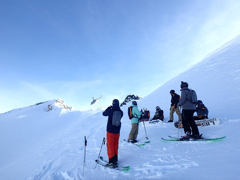 Skiers on top of mountain after being dropped off by a helicopter