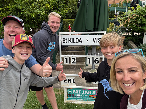 Kelly Ashfield poses with her family in front of a sport sign