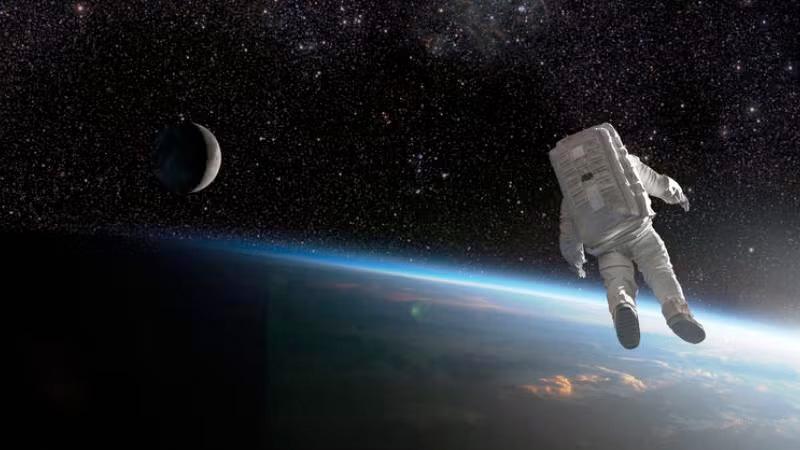 A composite image of an untethered astronaut in rear view, isolated and drifting off into deep space above the earth.