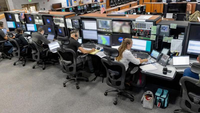 NASA employees sit at monitors in NASA control room