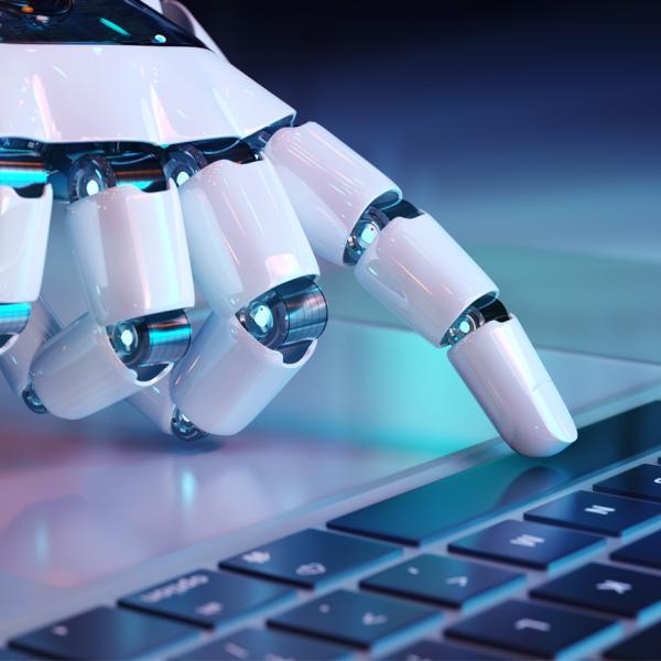 A robotic hand pressing the spacebar on a computer keyboard.