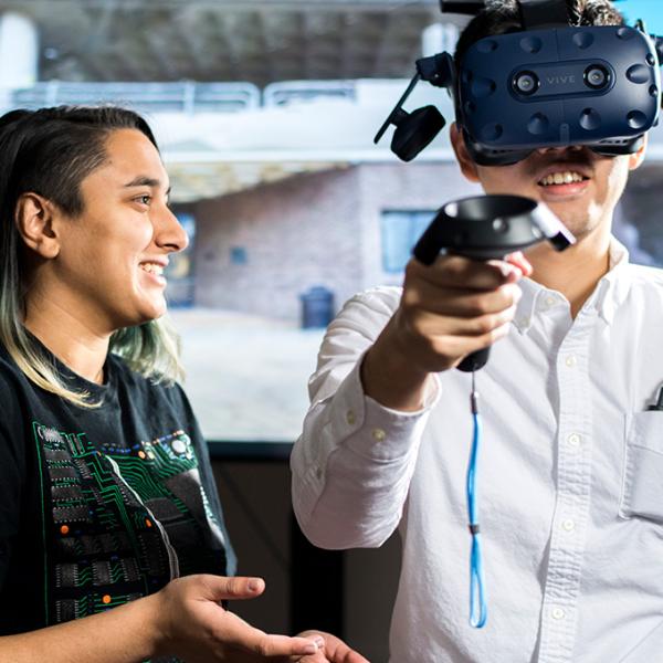 One person watching another using a virtual reality headset and controller.